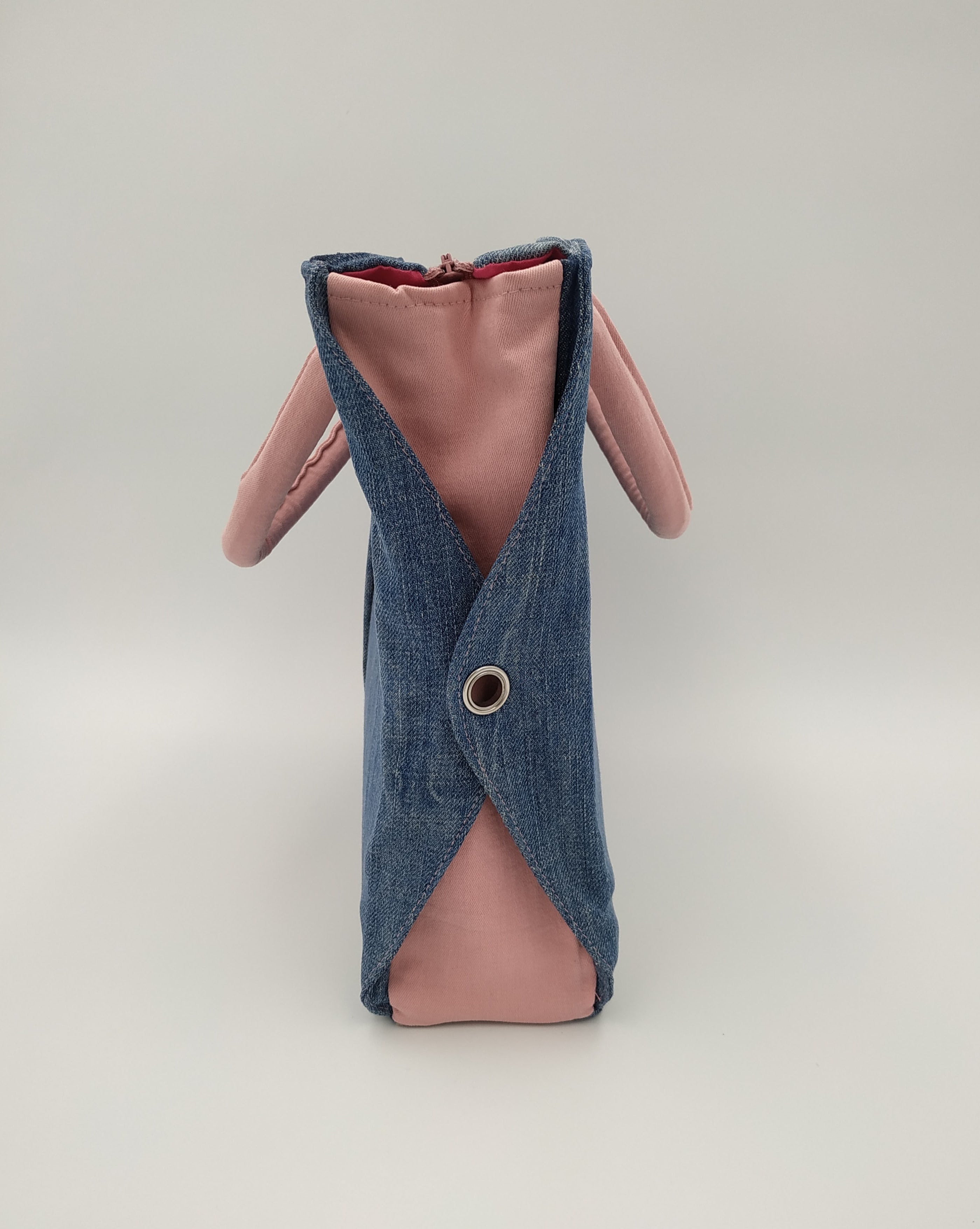 sac bicolore jean et rose - vue de côté avec les rabats jean percés d'un oeillet argenté sur fond de jean rose